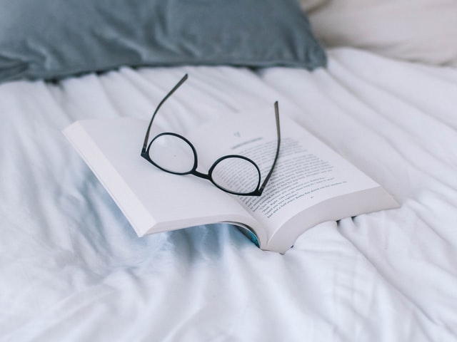 Black eyeglasses rest upon an open book.